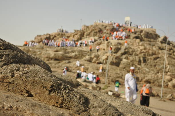 MECCA, SAUDI ARABIA - 08/08/2018 : Muslims praying at Mount Arafat (or Jabal Rahmah) during hajj. This is the place where Adam and Eve met after being overthrown from heaven.