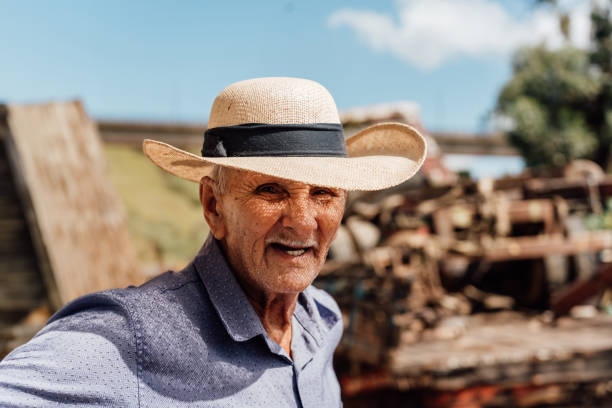 Closeup portrait of a sad senior man with a straw hat and sunglasses in a vintage Harcourt style lighting