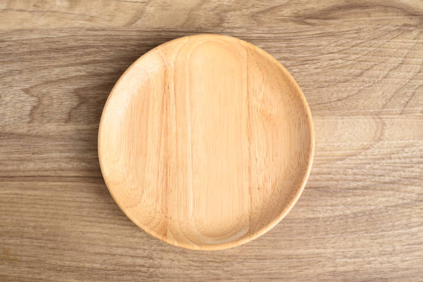 istock A wooden plate on wooden background, Table top view 2155230092