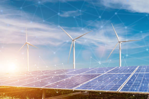 istock solar panels and wind turbines against connected to smart grid with sunset sky background. Photovoltaic, alternative electricity source. sustainable resources concept. 2155231188