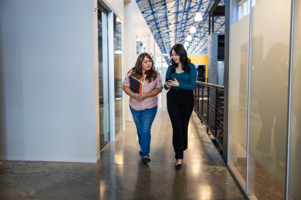 istock Co-Workers Walking Through the Office Sharing Information on a Phone 2155232938