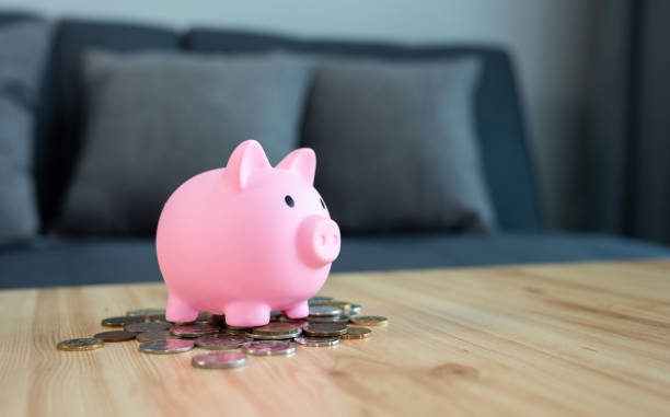 istock A pink piggy bank with various coins on table. 2155233545
