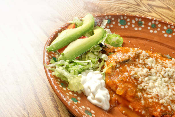 Mexican food dish on wooden tableChile rellenos or 'stuffed peppers' are a traditional Mexican dish made from roasted poblano peppers stuffed with cheese, then coated in a fluffy egg batter and fried
