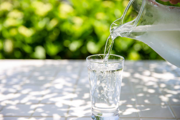 istock Pouring water: Drinking cold mineral water at a table in the shade 2155235677