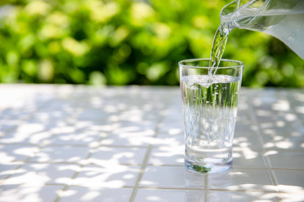 istock Pouring water: Drinking cold mineral water at a table in the shade 2155235682