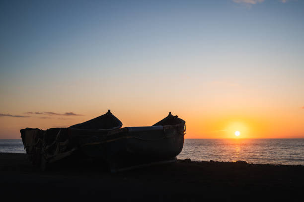 Two boats in a fishing village in Morocco and in the background the beginning of a sunset at sea.