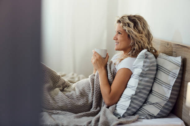 istock Relaxed woman enjoying in morning coffee in a bed. 2155247125