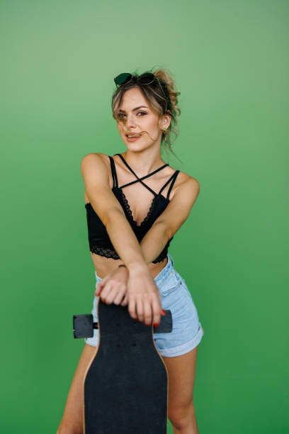 istock Young female skater posing on green background 2155247163