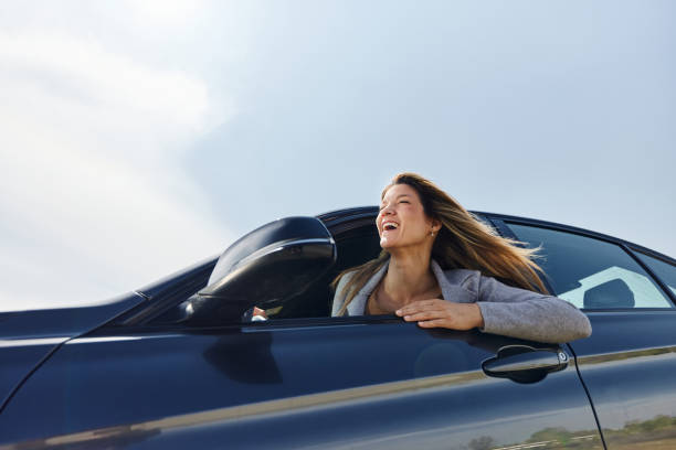 istock Below view of happy woman having fun while driving a car. 2155247532