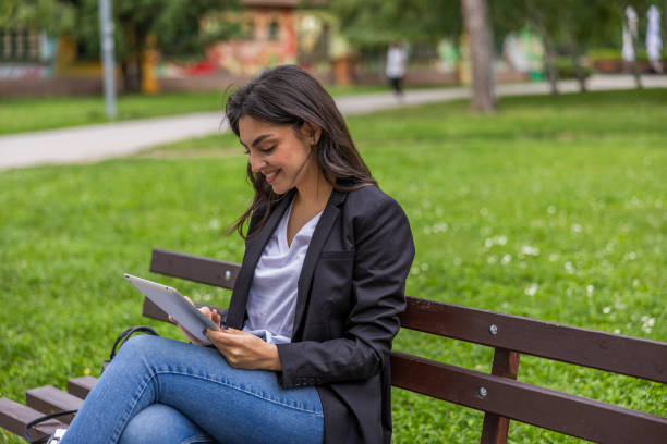 istock Business woman working on the digital tablet outdoors in the public park while resting and siting on the bench. 2155248666
