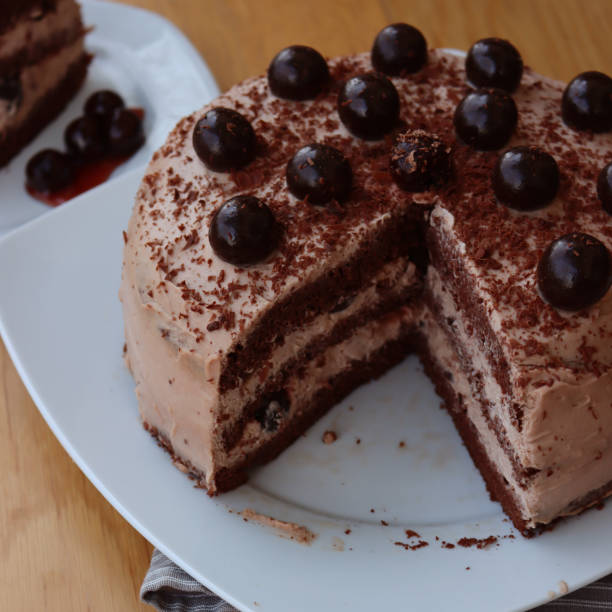 istock Sliced  chocolate cake with cocoa cream and sour cherries  on a plate on table 2155253599