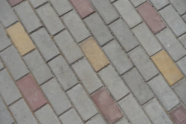 Texture of gray, pink and yellow concrete pavement with stretcher bond pattern