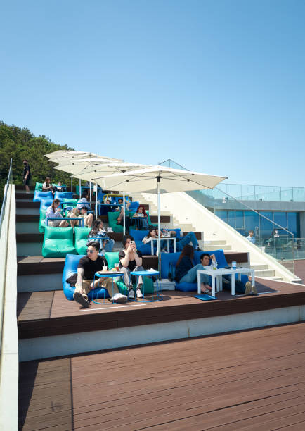 Busan, South Korea - May 18, 2024: Patrons enjoy a sunny day at a modern outdoor Cafe Coralani in Busan, South Korea, with comfortable seating and umbrellas