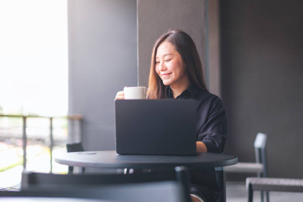 istock Portrait image of a young woman drinking coffee while working on laptop computer in cafe 2155254655