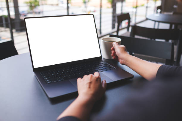istock Mockup image of a woman working on laptop computer with blank white desktop screen while drinking coffee in cafe 2155254658