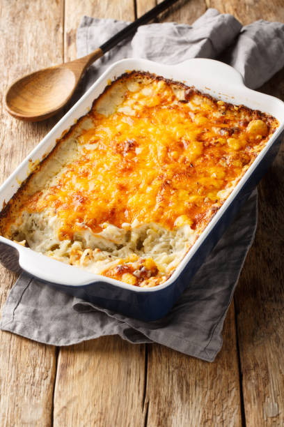 istock Hashbrown casserole with thickened creamy chicken soup and cheddar cheese close-up in a baking dish. Vertical 2155258876