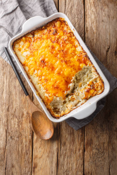istock Hashbrown casserole with thickened creamy chicken soup and cheddar cheese close-up in a baking dish. Vertical top view 2155258910
