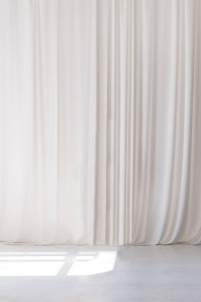 istock White curtain that dropped down as a straight line. White wooden floor. Background for inserting text, empty spaces. 2155258965