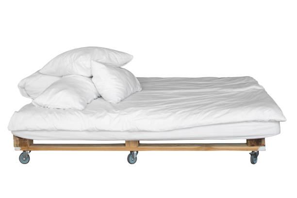 Pallet bed with white bedding and pillows. Mobile bed on wheels. Isolated on white background