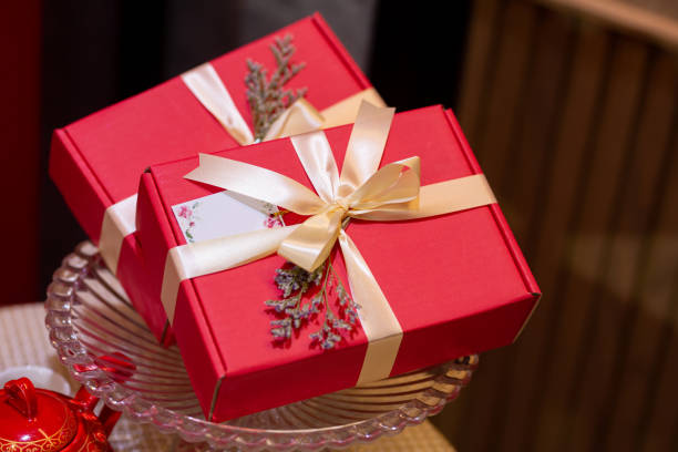 istock 2 red gift boxes tied with golden bows overlapping, copy space spaced 2155260534