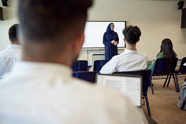 istock Mature female teacher explaining university students sitting in classroom 2155267410