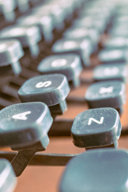 Closeup of vintage worn out typewriter and various keys with dust while placed on wooden table in daylight against dark blurred room
