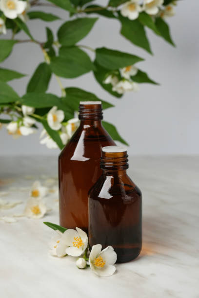 istock Jasmine essential oil (tincture, remedy, infusion) bottles with fresh jasmine flowers on white marble background. 2155270505