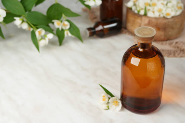 istock Cosmetic oil (perfume) with jasmine essence on marble table. Side view. Space for text. 2155270507