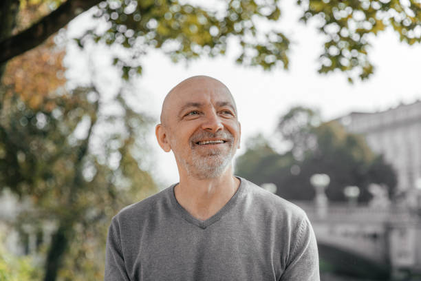 istock Happy senior man in grey sweater sitting in a park, smiling warmly 2155278231
