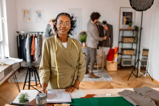 istock Young female tailor standing at the desk in her small clothing design studio. 2155289146