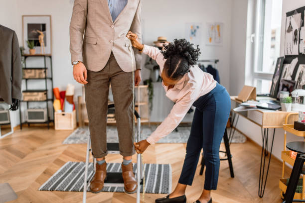 istock Young female tailor taking measures of customer at tailor workshop 2155290496