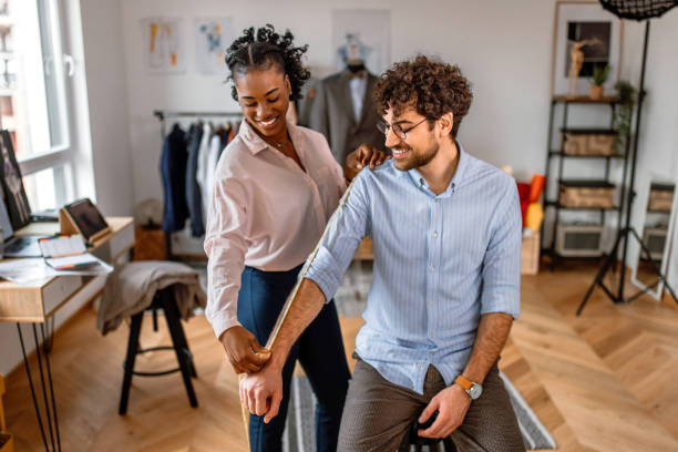 istock Young female tailor taking measures of customer at tailor workshop 2155290856