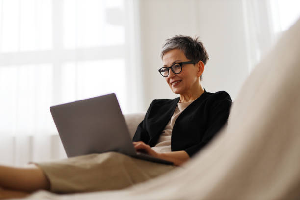 istock A comfortable businesswoman works remotely from her sofa, typing on her laptop, enjoying modern technology. 2155293358