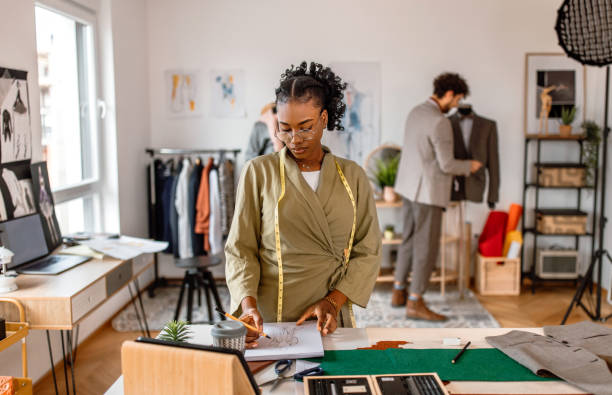 istock Young female tailor standing at the desk in her small clothing design studio. 2155298528