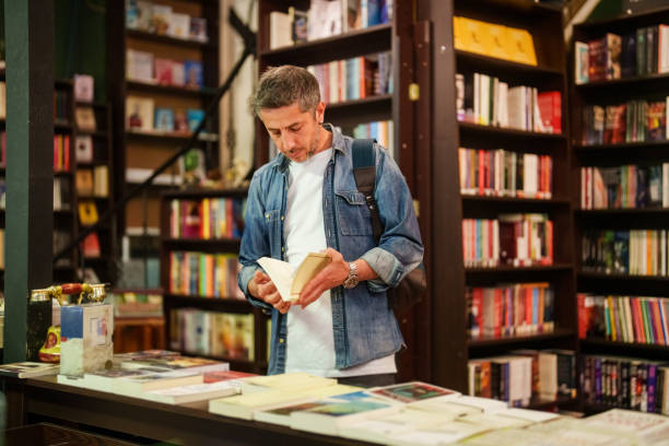 istock Man examining the books in bookstore shelves. 2155300003