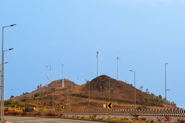 Serene highway scene with wind turbines atop a distant hill, symbolizing sustainable energy.