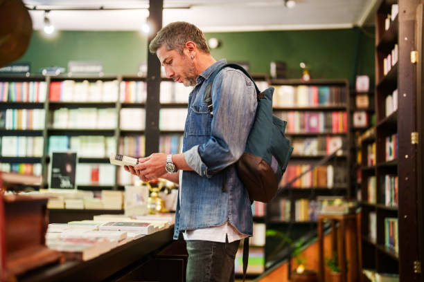 istock Man examining the books in bookstore shelves. 2155300242