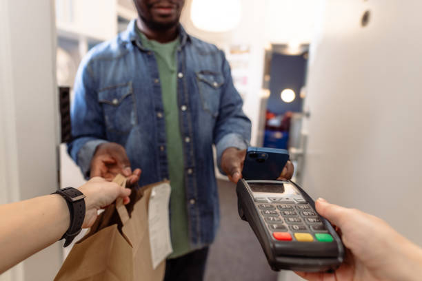 istock Food delivery person completing payment transaction with a card reader 2155300896