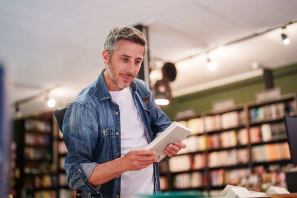 istock Man examining the books in bookstore shelves. 2155300959