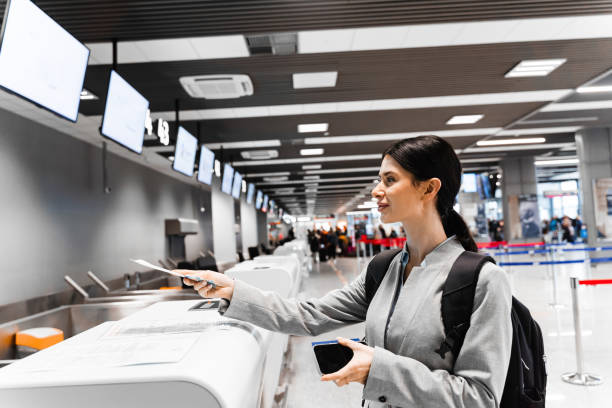istock Caucasian woman checking in at the terminal counter. A traveler holds documents during check in at the airport terminal desk. 2155302021