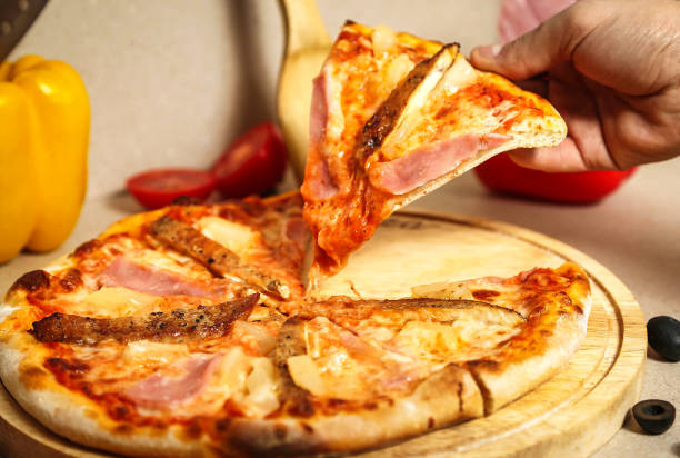 istock Person Taking a Slice of Ham and Cheese Pizza 2155303036