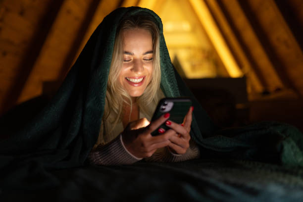 istock Smiling woman using mobile phone while relaxing on sofa in mountain house 2155306177