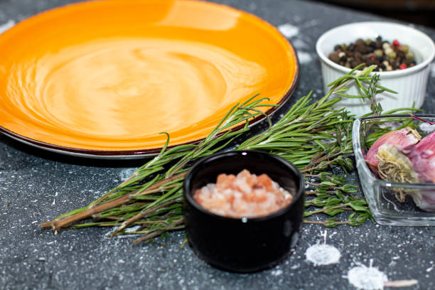 Empty orange plate of spices and herbs on a black table close-up