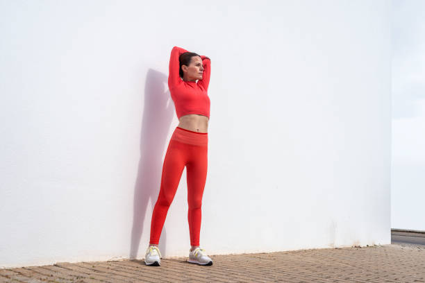 istock Sporty woman doing an arm stretch exercise, outside, white wall. 2155310285