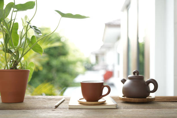 istock Tea cup and earthenware teapot at the balcony and notebooks side view 2155313325