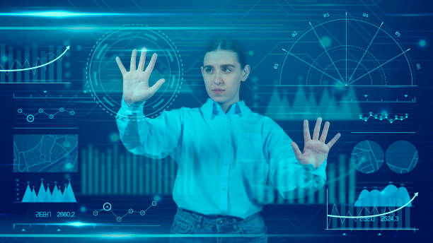 istock Woman looking and touching data analysis screen with virtual reality glasses.View of a young businesswoman using Graphical User Interface with VR glasses. She’s working on a new project. She looks very busy. Blue hologram. Analytics 2155317306