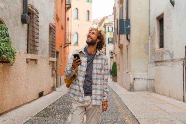 Man using smartphone while walking on quaint street in Verona