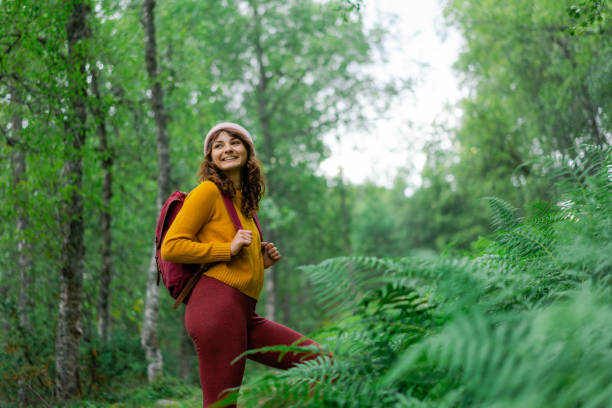 Serene woman  hiking through dense forest in Norway