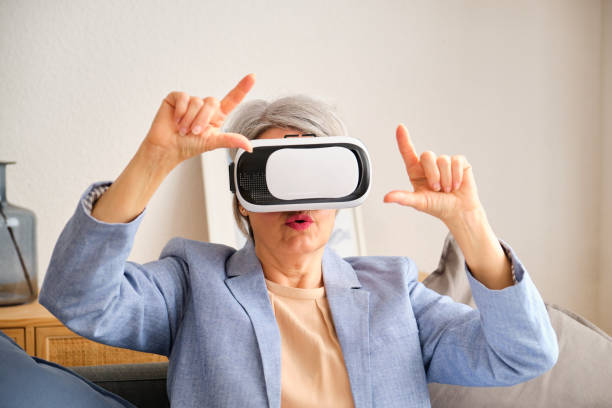 istock A mature woman is playing a video game with a virtual reality headset on. 2155318176