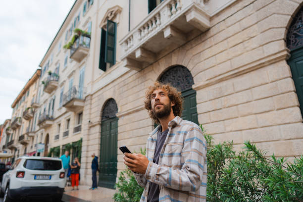 istock Man using smartphone while walking on quaint street in Verona 2155318434